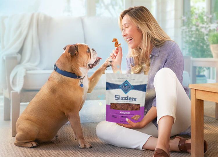 Blue Buffalo - A woman sitting on the floor with her dog, enjoying a peaceful moment together with Blue Sizzlers Dog Treats food