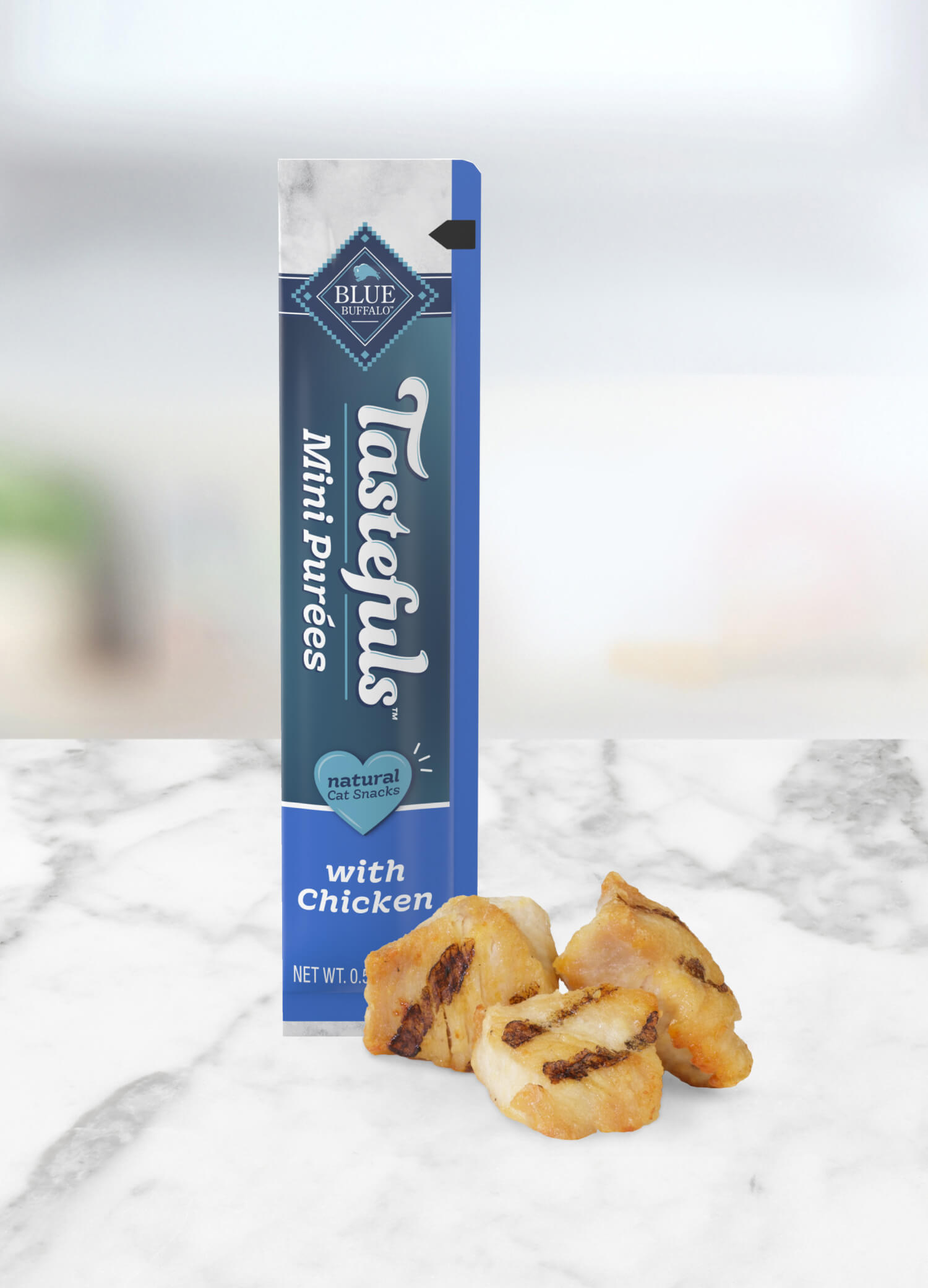 A tube of BLUE Tastefuls Mini Purees and chunks of grilled chicken are on a kitchen counter